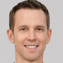 Joyful white adult male with short  brown hair and grey eyes