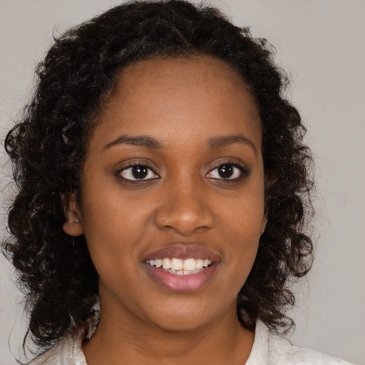 Joyful black young-adult female with long  brown hair and brown eyes