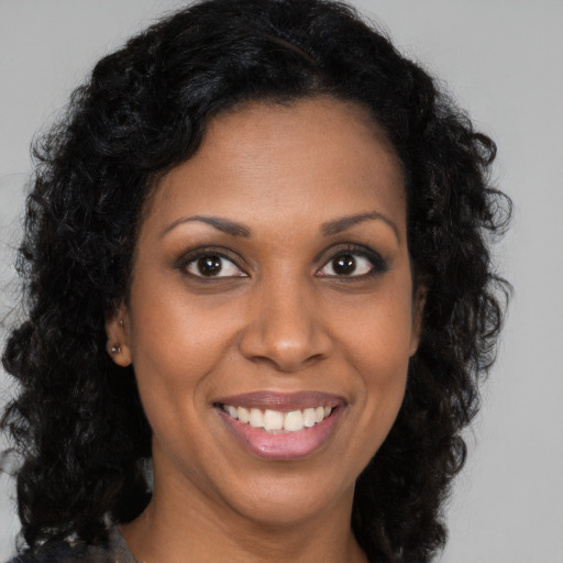 Joyful black young-adult female with long  brown hair and brown eyes