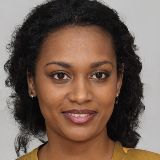 Joyful black young-adult female with long  brown hair and brown eyes