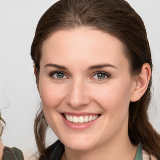 Joyful white young-adult female with medium  brown hair and grey eyes