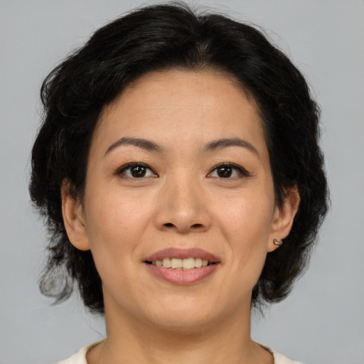 Joyful asian adult female with medium  brown hair and brown eyes