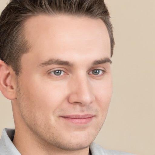 Joyful white young-adult male with short  brown hair and grey eyes