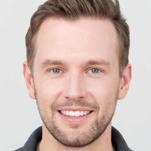 Joyful white young-adult male with short  brown hair and grey eyes