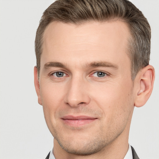 Joyful white young-adult male with short  brown hair and grey eyes