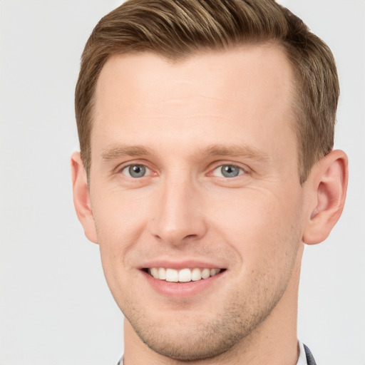 Joyful white young-adult male with short  brown hair and grey eyes