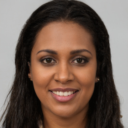 Joyful black young-adult female with long  brown hair and brown eyes