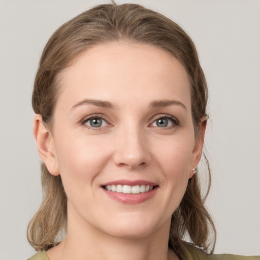 Joyful white young-adult female with medium  brown hair and grey eyes