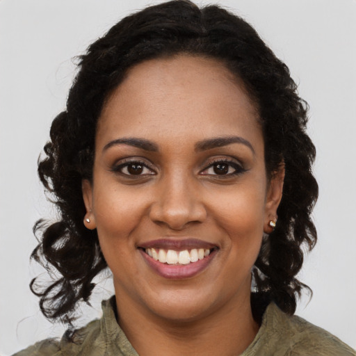 Joyful black young-adult female with long  brown hair and brown eyes