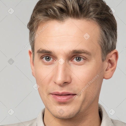 Joyful white young-adult male with short  brown hair and grey eyes