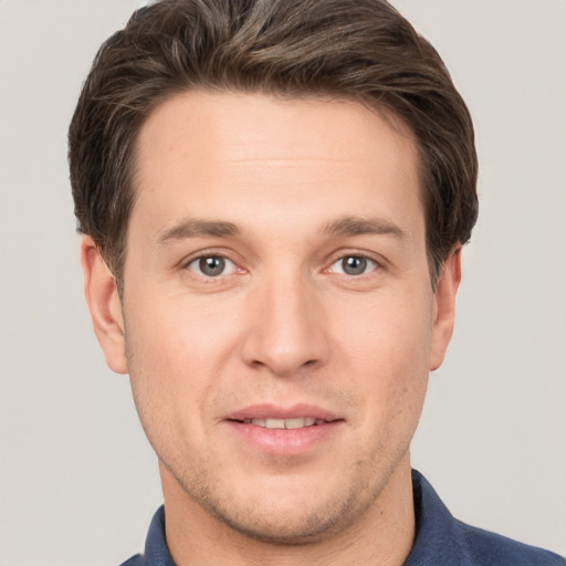 Joyful white young-adult male with short  brown hair and grey eyes