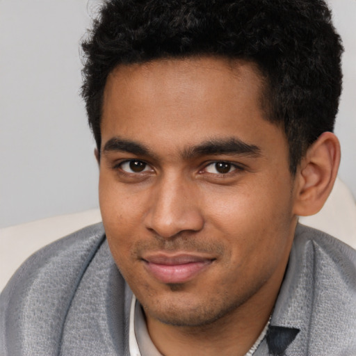 Joyful black young-adult male with short  brown hair and brown eyes
