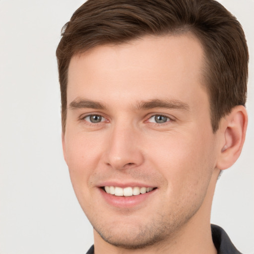 Joyful white young-adult male with short  brown hair and grey eyes