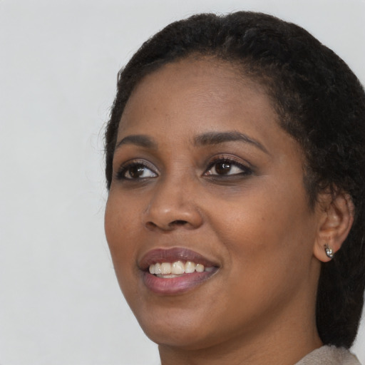 Joyful black young-adult female with long  black hair and brown eyes