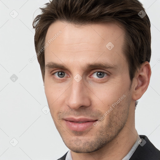 Joyful white young-adult male with short  brown hair and grey eyes