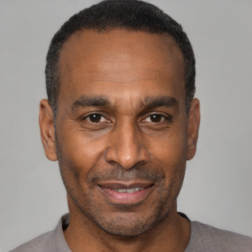 Joyful black adult male with short  black hair and brown eyes