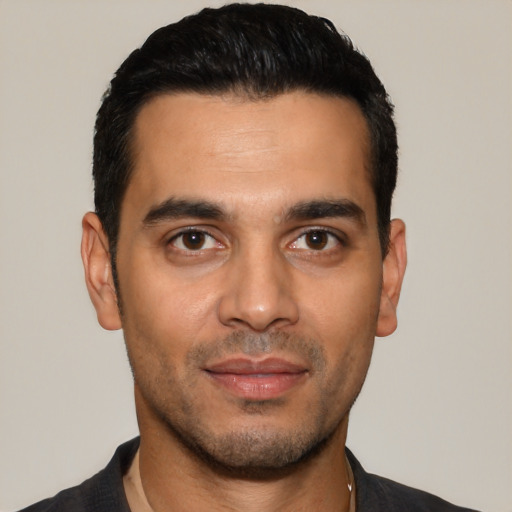 Joyful latino young-adult male with short  black hair and brown eyes