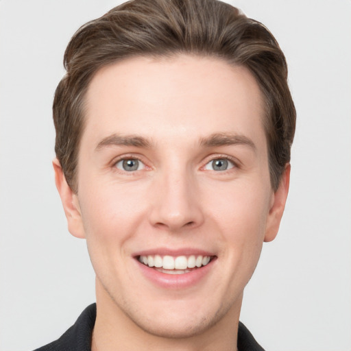 Joyful white young-adult male with short  brown hair and grey eyes