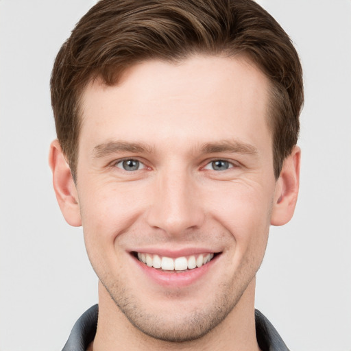 Joyful white young-adult male with short  brown hair and grey eyes