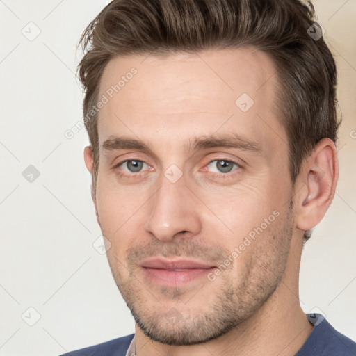 Joyful white young-adult male with short  brown hair and grey eyes