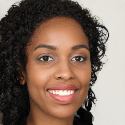 Joyful black young-adult female with long  brown hair and brown eyes