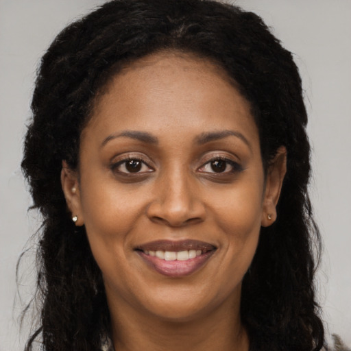 Joyful black adult female with long  brown hair and brown eyes