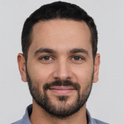 Joyful white young-adult male with short  black hair and brown eyes