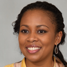 Joyful black young-adult female with long  brown hair and brown eyes