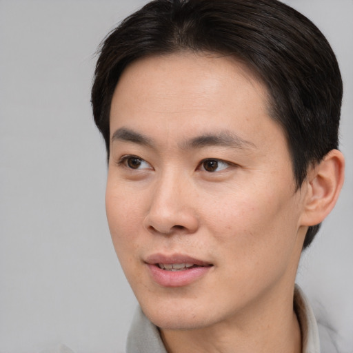 Joyful asian young-adult male with short  brown hair and brown eyes