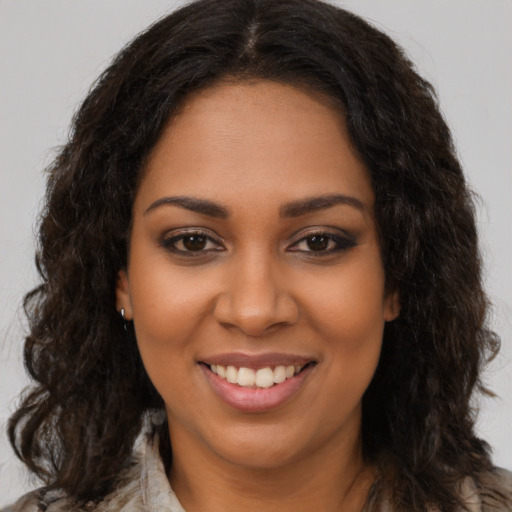 Joyful black young-adult female with long  brown hair and brown eyes