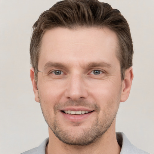 Joyful white young-adult male with short  brown hair and grey eyes