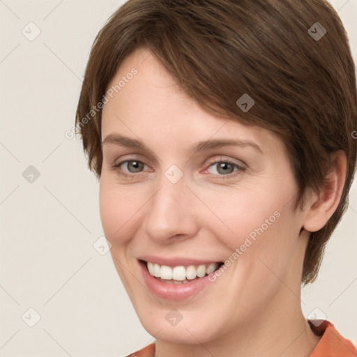 Joyful white young-adult female with short  brown hair and grey eyes