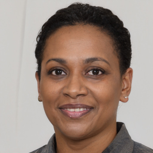 Joyful black adult female with short  black hair and brown eyes