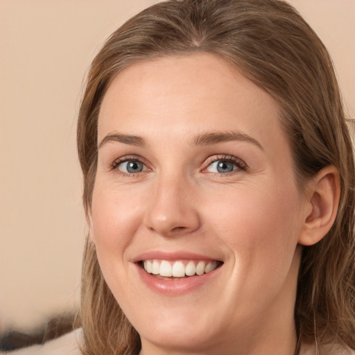 Joyful white young-adult female with long  brown hair and blue eyes