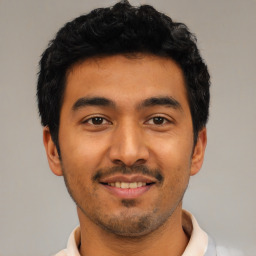 Joyful latino young-adult male with short  black hair and brown eyes