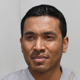 Joyful latino young-adult male with short  black hair and brown eyes