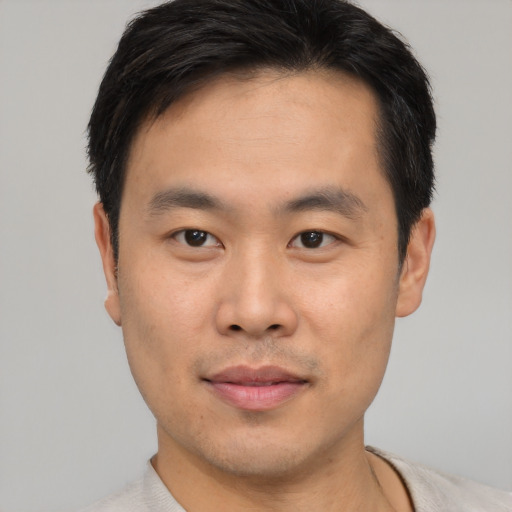 Joyful asian young-adult male with short  black hair and brown eyes