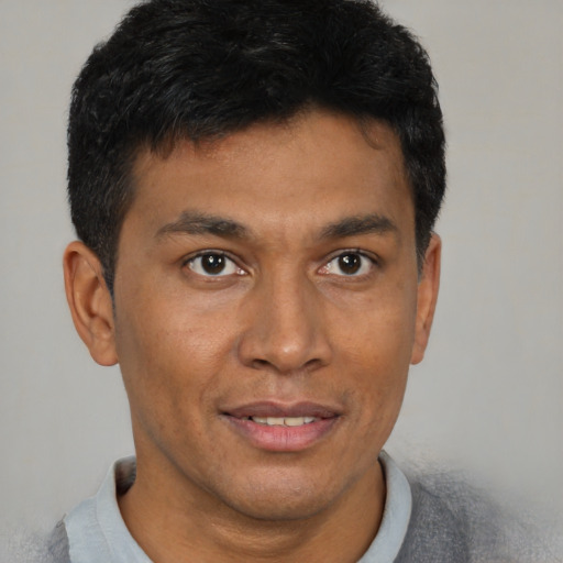 Joyful black young-adult male with short  brown hair and brown eyes