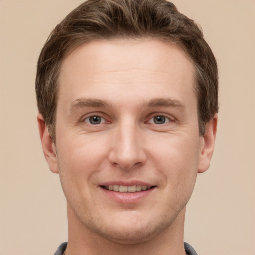 Joyful white young-adult male with short  brown hair and grey eyes