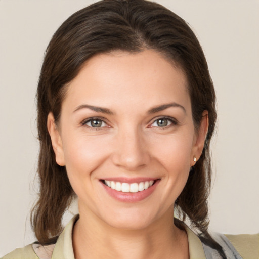 Joyful white young-adult female with medium  brown hair and grey eyes