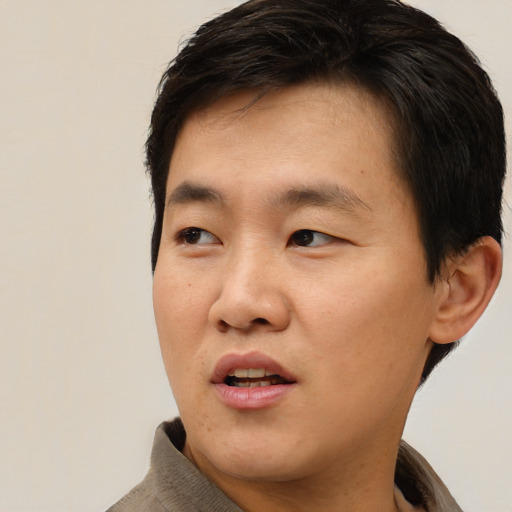 Joyful asian young-adult male with short  brown hair and brown eyes