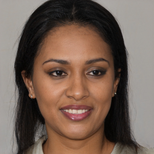 Joyful black young-adult female with long  brown hair and brown eyes