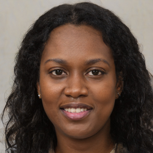 Joyful black young-adult female with long  black hair and brown eyes