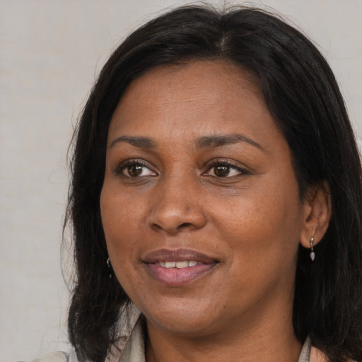 Joyful black adult female with long  brown hair and brown eyes