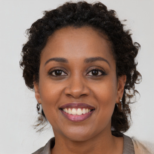 Joyful black young-adult female with long  brown hair and brown eyes