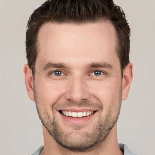 Joyful white young-adult male with short  brown hair and grey eyes