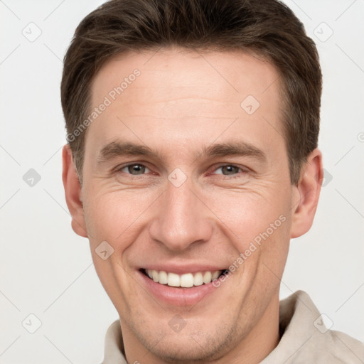 Joyful white young-adult male with short  brown hair and grey eyes