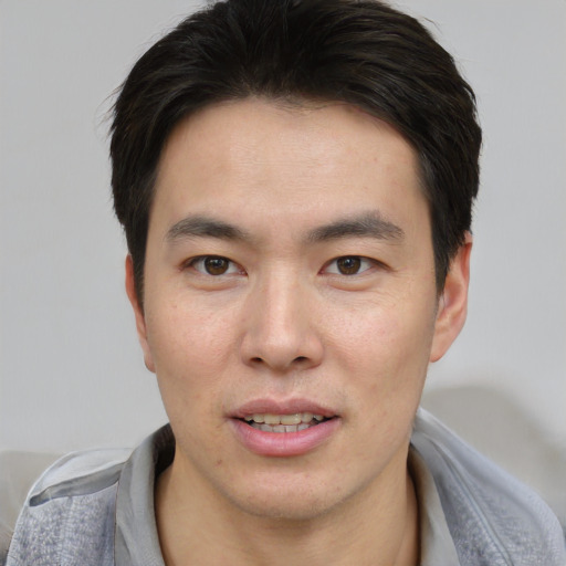 Joyful asian young-adult male with short  brown hair and brown eyes