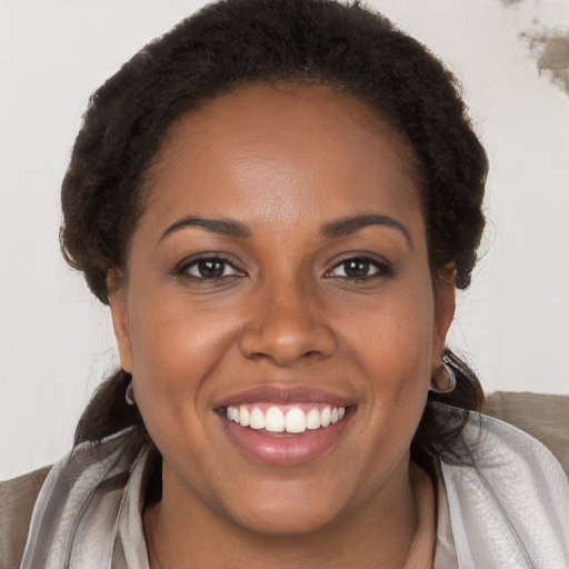 Joyful black young-adult female with long  brown hair and brown eyes