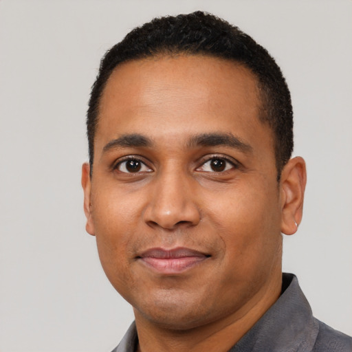 Joyful black young-adult male with short  black hair and brown eyes
